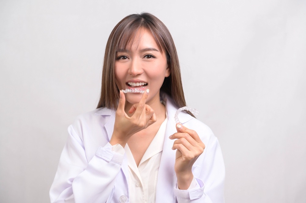 young orthodontist holding Invisalign clear aligners as one of her choices between aligners vs braces in charlottesville, va