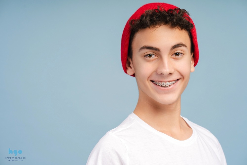 a boy with red beanie and metal braces smiling at the camera after understanding how long do braces take in charlottesville, va
