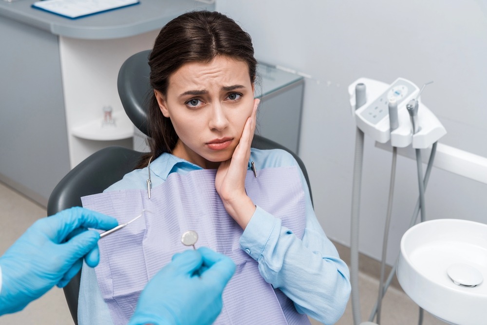 selective focus dentist latex gloves holding dental instruments upset woman - TMJ Treatment in Charlottesville, VA