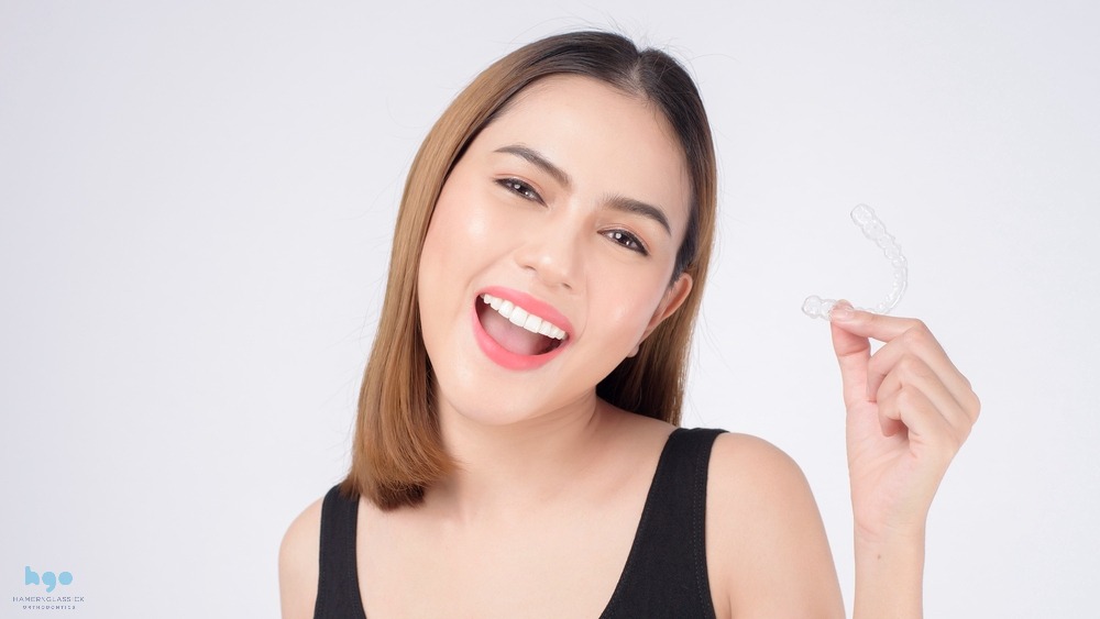 young smiling woman holding invisalign clear aligners studio dental healthcare orthodontic - How Does Invisalign Work in Charlottesville, VA 